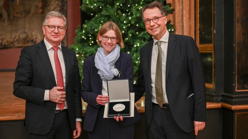 Mittig Dr. Stephanie Herrmann mit der Georg-Maurer-Medaille in der Hand, links Dr. Martin Siess und rechts von ihr Prof. Peter Henningsen 