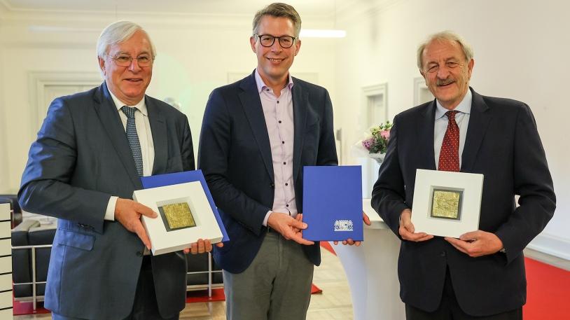 Staatsminister Markus Blumein der Mitte, Prof. Markus Schwaiger rechts und Prof. Karl-Walter Jauch links stehend mit Auszeichnung in der Hand 