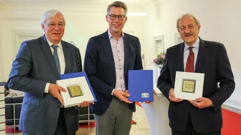 Staatsminister Markus Blumein der Mitte, Prof. Markus Schwaiger rechts und Prof. Karl-Walter Jauch links stehend mit Auszeichnung in der Hand